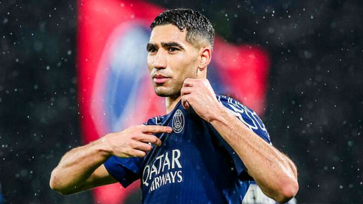 Achraf Hakimi montrant le blason du PSG sur son maillot.